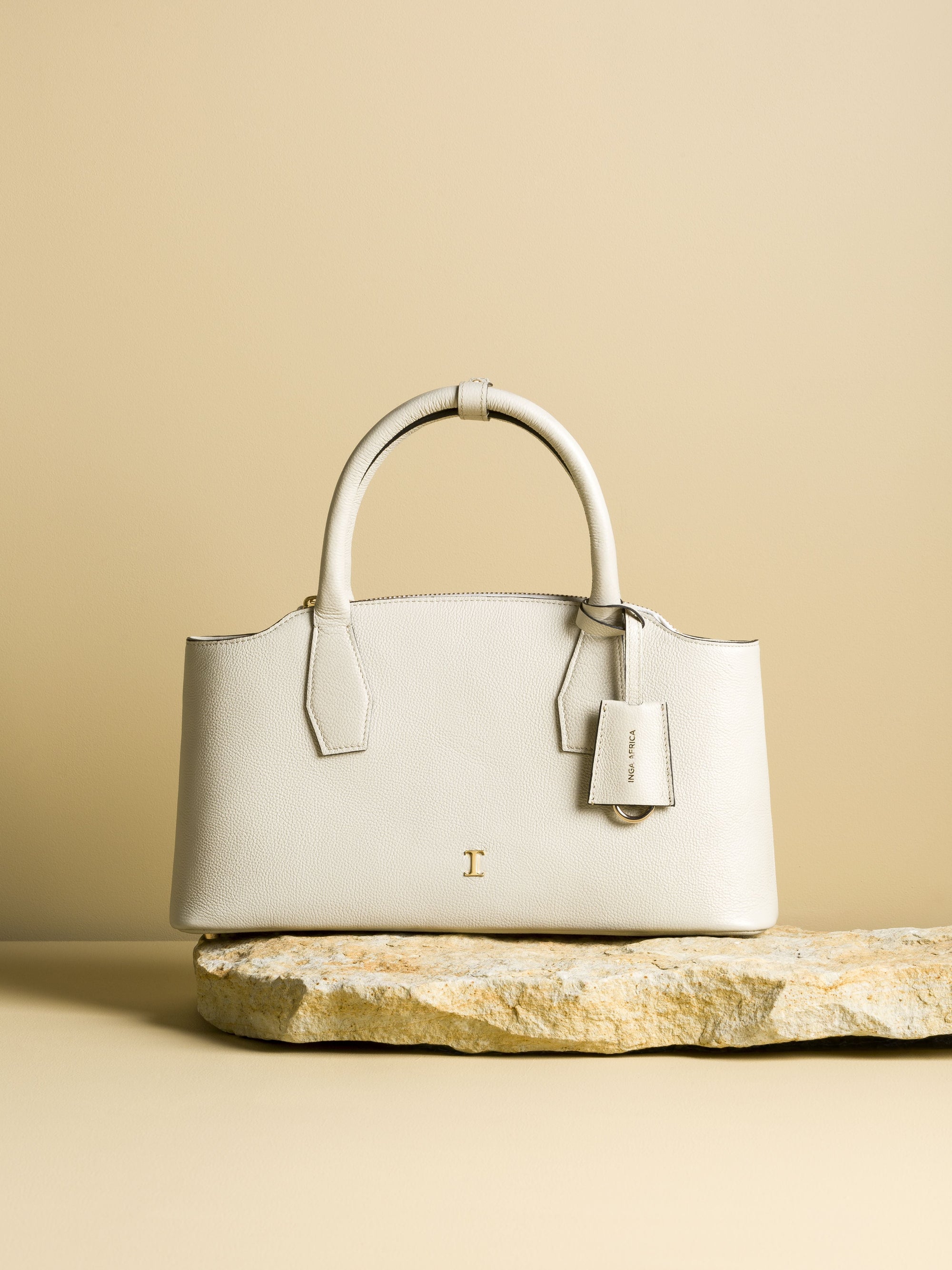 White handbag on a stone surface with a beige background