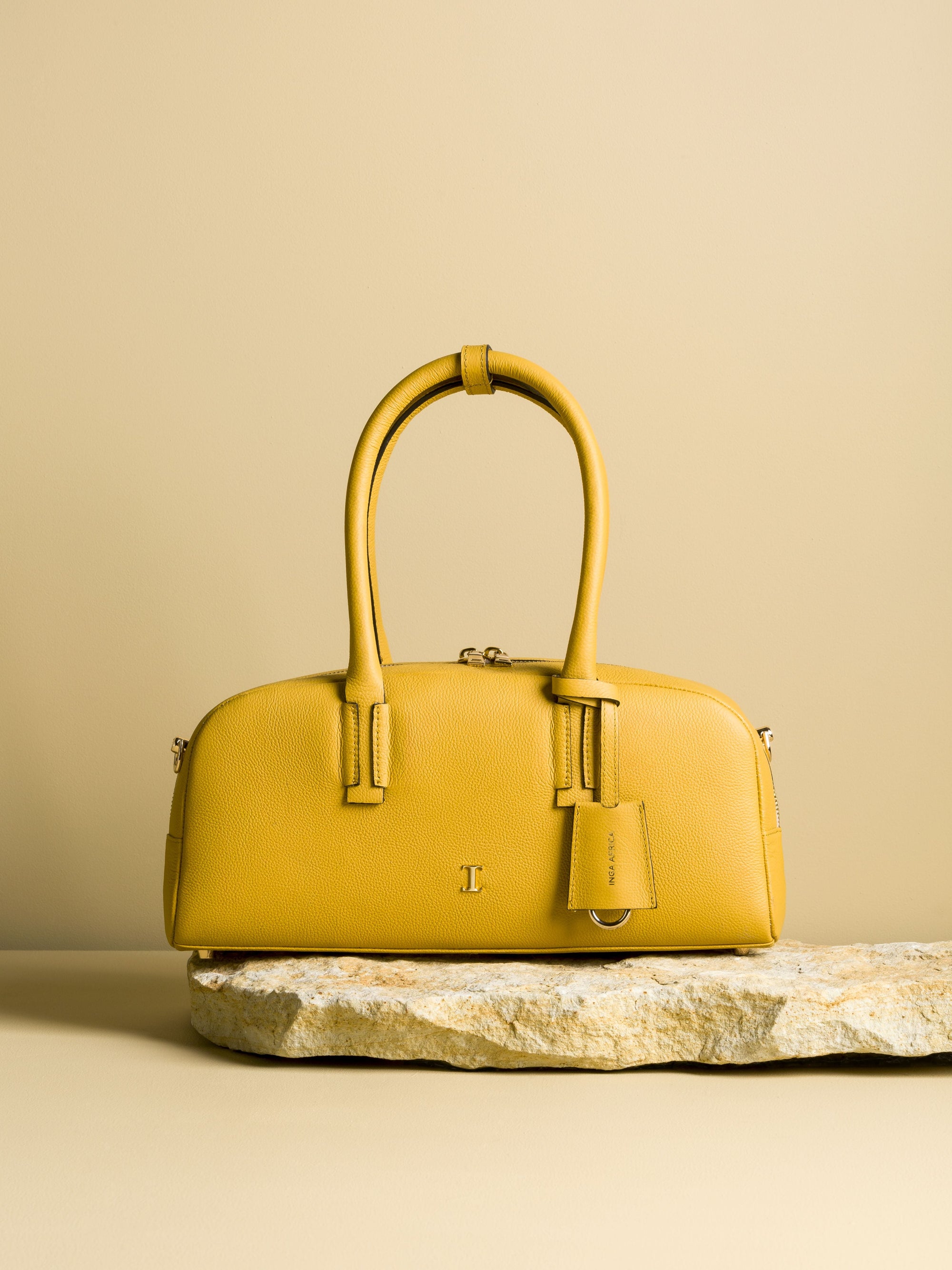 Yellow handbag on a stone surface with a beige background