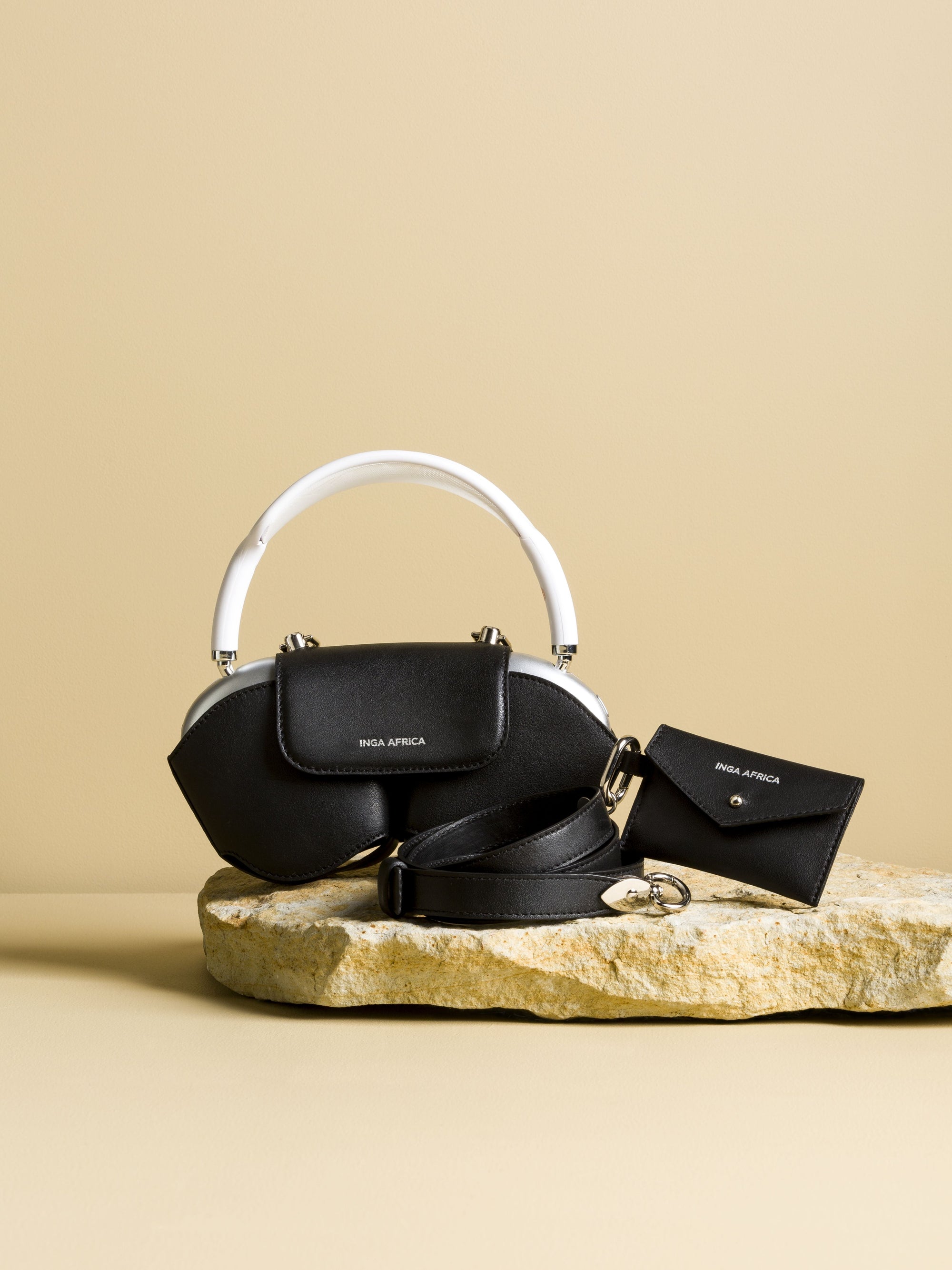 Black handbag with white handle and matching wallet on a beige background