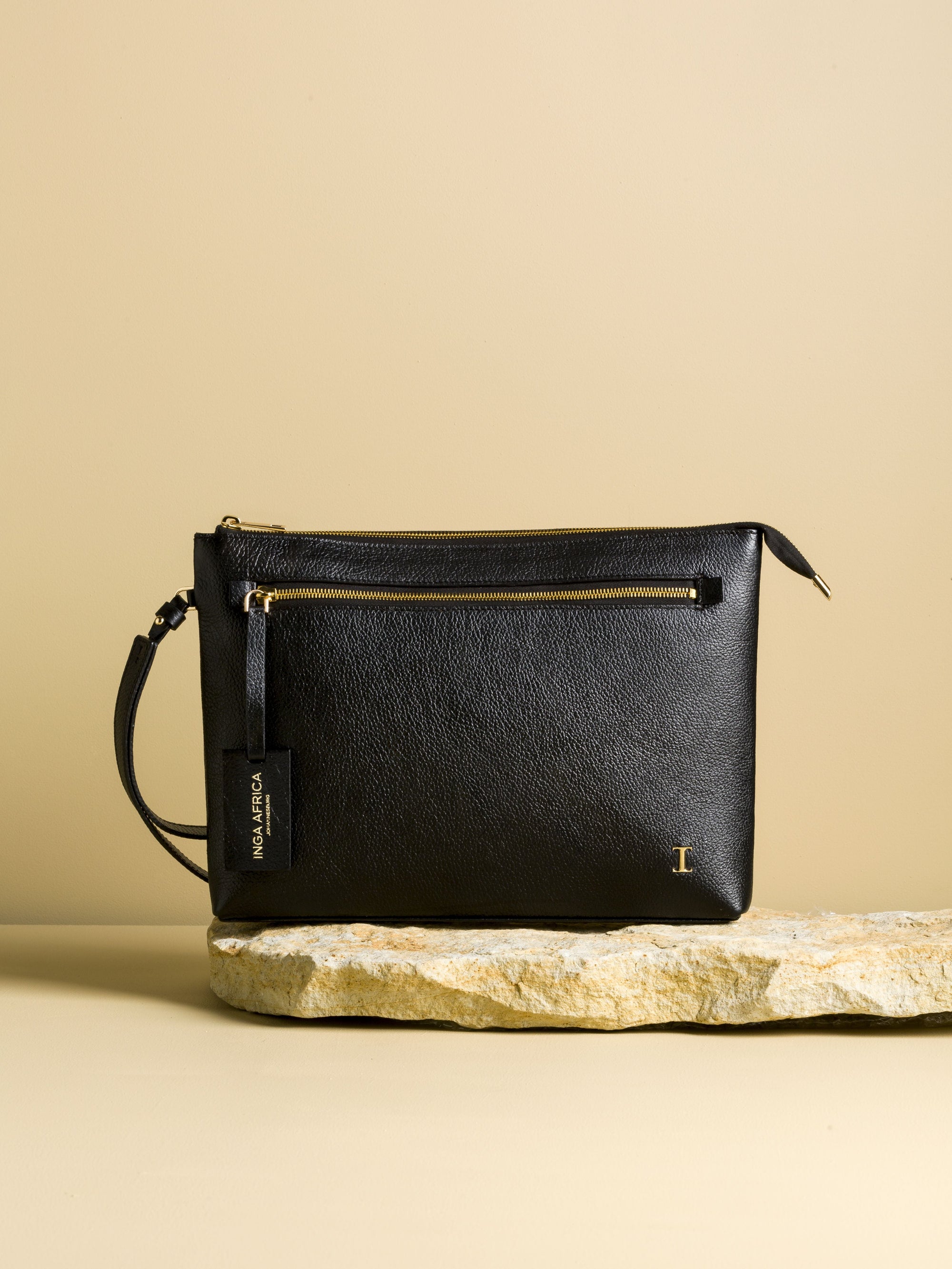Black leather handbag on a stone surface with a beige background