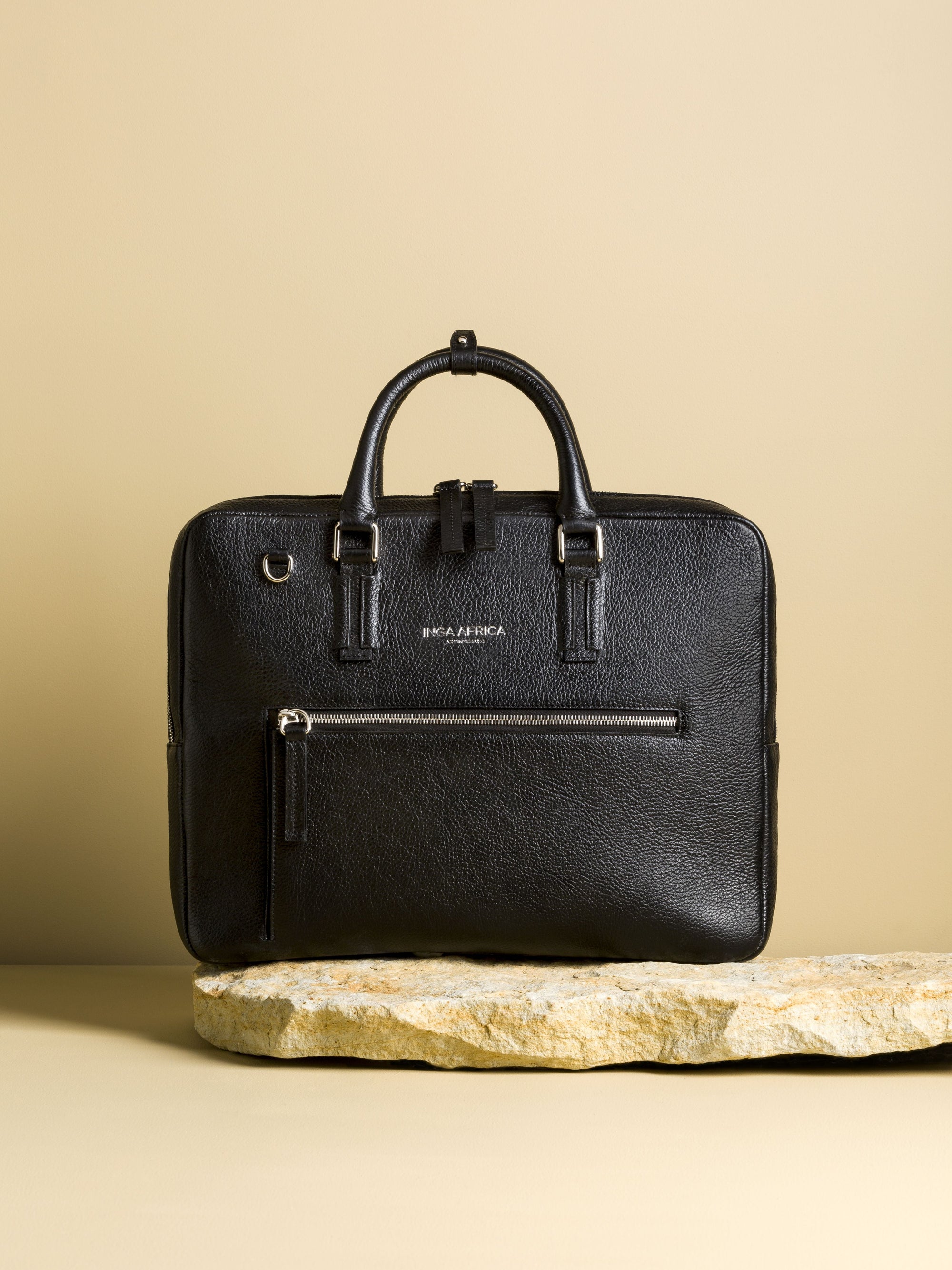 Black leather briefcase on a stone surface with a beige background
