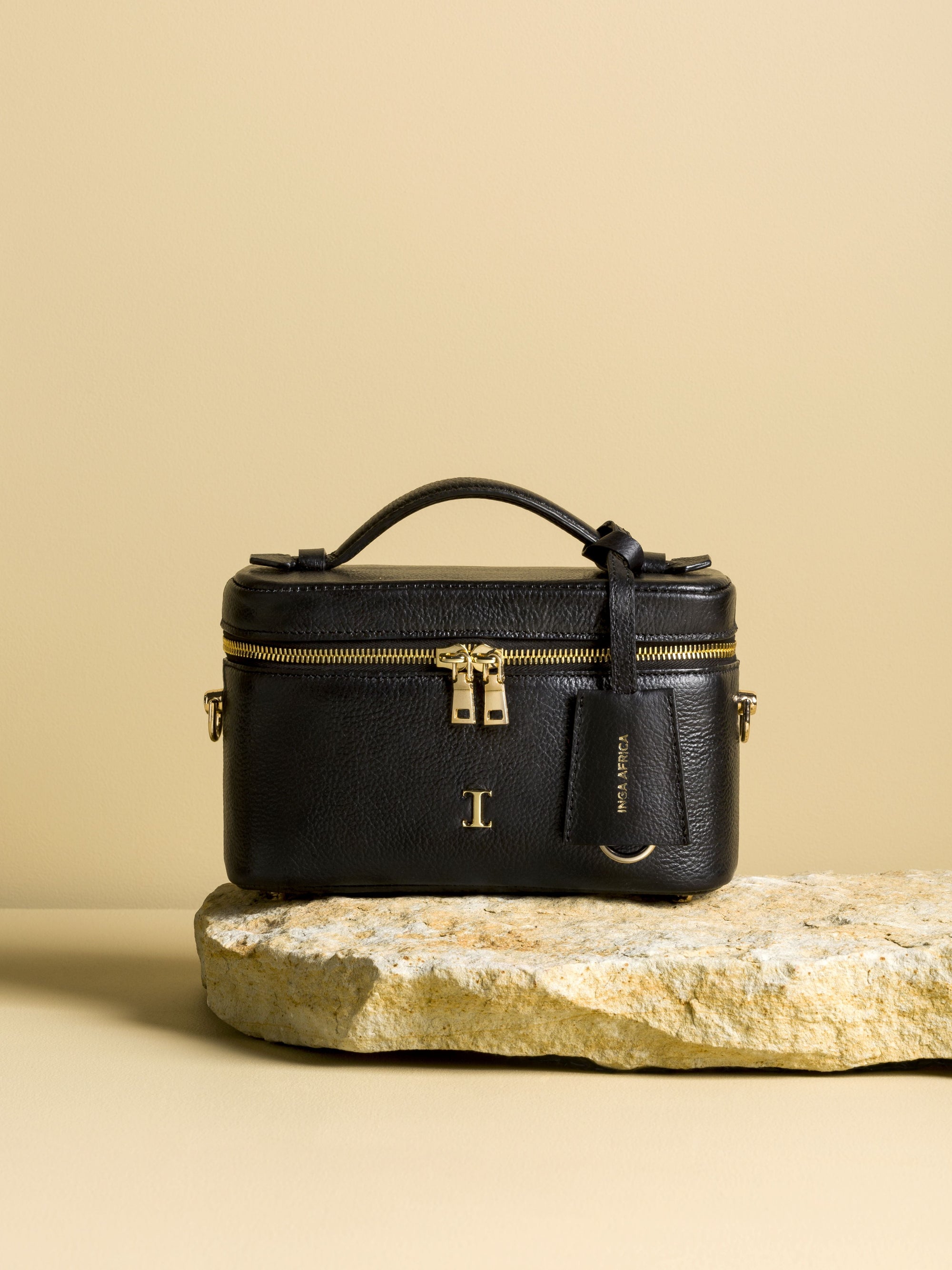 Black handbag with gold accents on a beige background